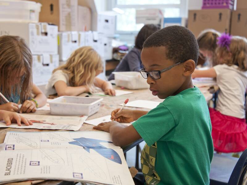 Kinder sitzen an einem Tisch und arbeiten an AUfgaben