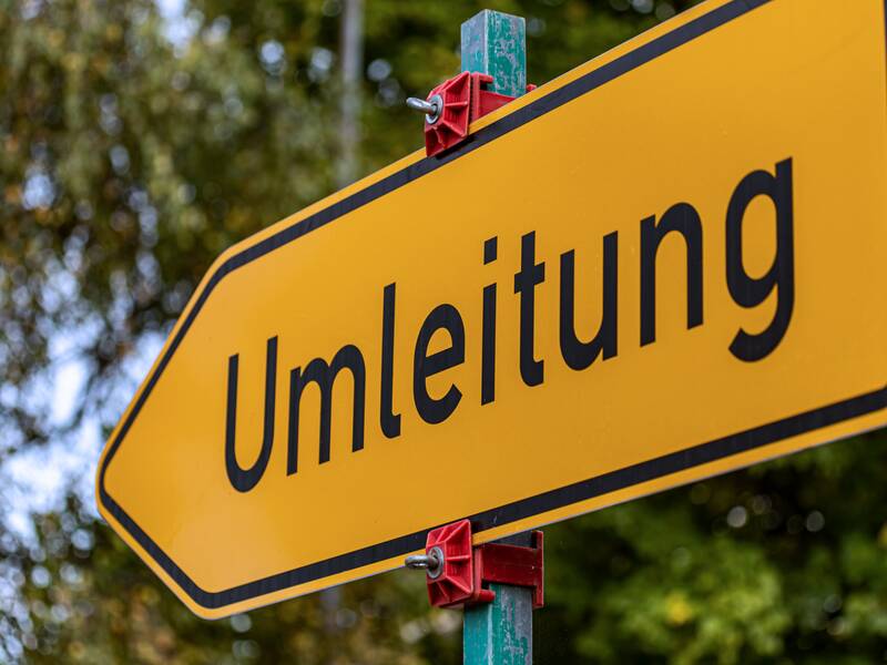 Ein gelbes Umleitungsschild, das in die linke Richtung zeigt.