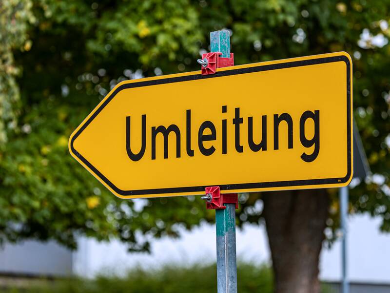 Ein gelbes Umleitungsschild, das in die linke Richtung zeigt.